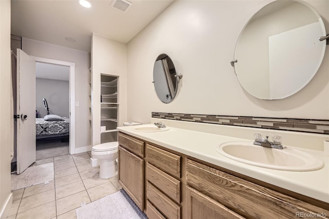 ensuite bathroom featuring a sink, toilet, visible vents, tile patterned flooring, and double vanity