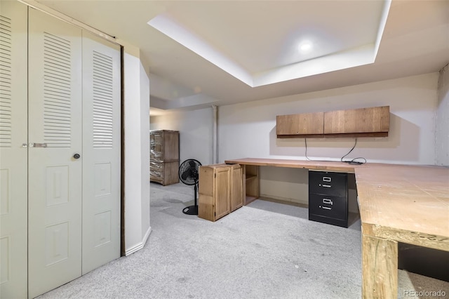 unfurnished office with baseboards, a raised ceiling, and light colored carpet