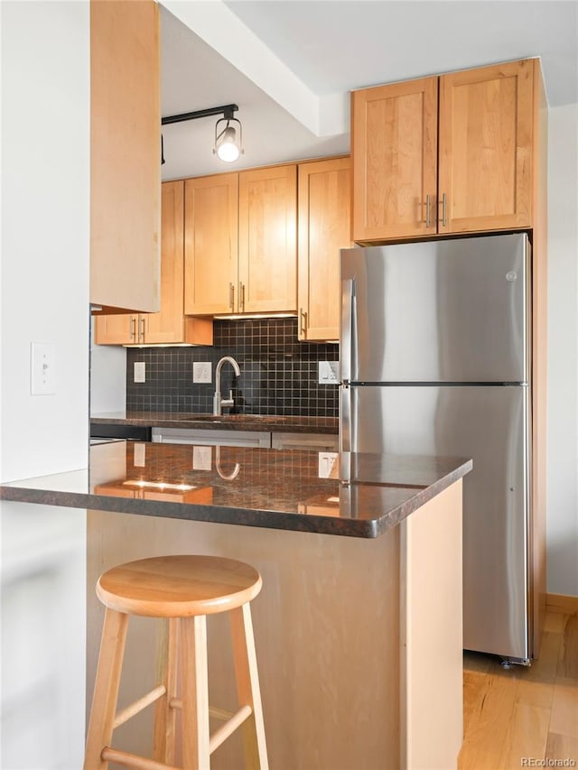 150 Evergreen Rd Unit 204, Dillon, CO 80435 - kitchen with freestanding refrigerator, light brown cabinetry, decorative backsplash, a sink, and a kitchen breakfast bar