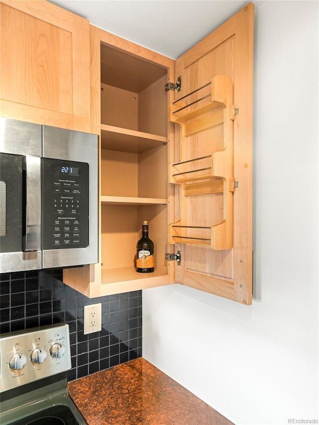 150 Evergreen Rd Unit 204, Dillon, CO 80435 - kitchen view of stainless steel microwave, backsplash, dark countertops, light brown cabinets, and range