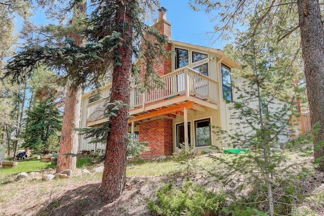 8795 Rudd Rd, Evergreen, CO 80439 - rear view of house featuring a chimney, a deck, and brick siding