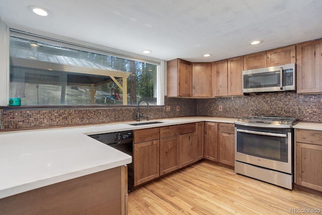 8795 Rudd Rd, Evergreen, CO 80439 - kitchen featuring stainless steel appliances, a sink, light wood-type flooring, tasteful backsplash, and light countertops