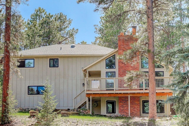 8795 Rudd Rd, Evergreen, CO 80439 - back of property featuring a deck, a chimney, stairs, and a shingled roof