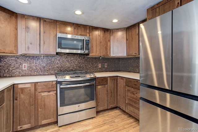 8795 Rudd Rd, Evergreen, CO 80439 - kitchen with appliances with stainless steel finishes, light wood-style flooring, light countertops, tasteful backsplash, and recessed lighting