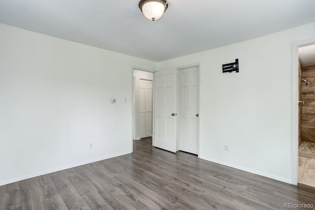 8795 Rudd Rd, Evergreen, CO 80439 - unfurnished bedroom featuring wood finished floors, baseboards, and connected bathroom