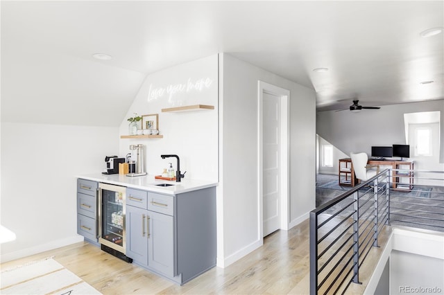 interior space with ceiling fan, gray cabinetry, lofted ceiling, wine cooler, and sink