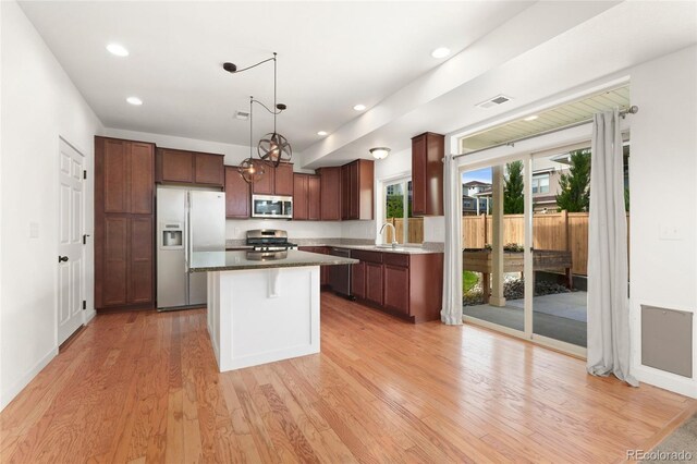 3692 Celestial Ave, Castle Rock, CO 80109 - kitchen with appliances with stainless steel finishes, light wood-type flooring, a center island, a sink, and a kitchen breakfast bar