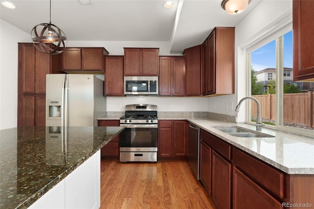 3692 Celestial Ave, Castle Rock, CO 80109 - kitchen with stainless steel appliances, a sink, light wood-style flooring, dark stone counters, and decorative light fixtures