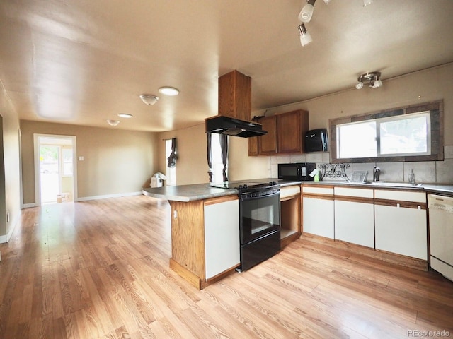 kitchen with kitchen peninsula, black appliances, a wealth of natural light, and light hardwood / wood-style flooring