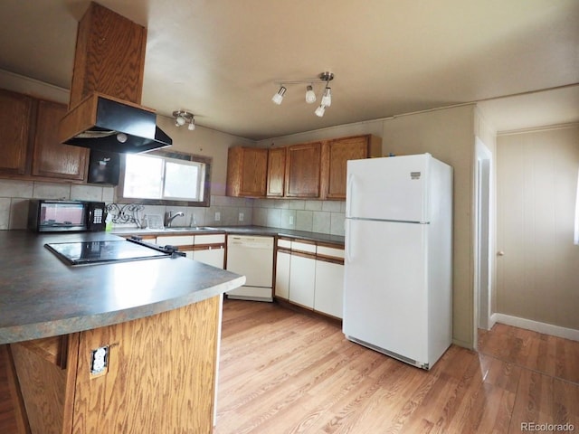 kitchen with white appliances, light wood-style floors, decorative backsplash, a sink, and under cabinet range hood