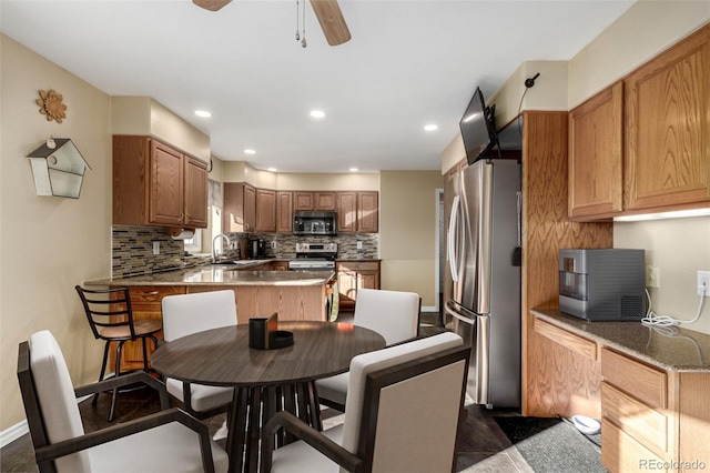 kitchen with stainless steel appliances, sink, ceiling fan, and decorative backsplash