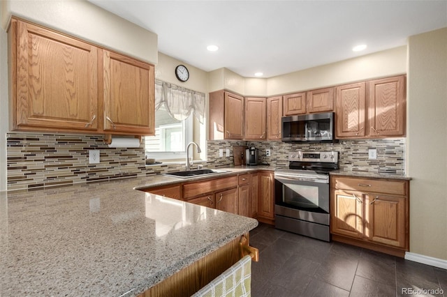 kitchen featuring appliances with stainless steel finishes, sink, light stone counters, and decorative backsplash