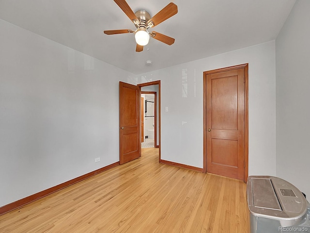 empty room with a ceiling fan, light wood-style flooring, and baseboards