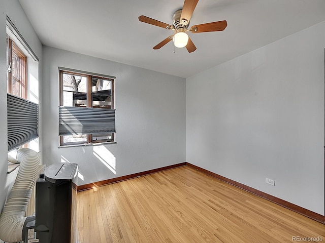 unfurnished room with wood finished floors, baseboards, and a ceiling fan