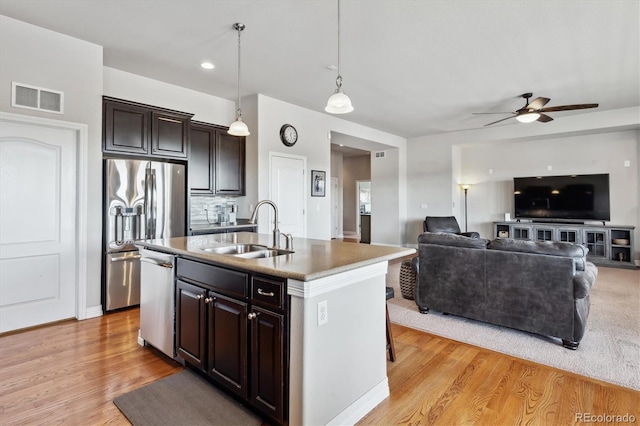 kitchen featuring light wood finished floors, visible vents, a sink, appliances with stainless steel finishes, and a kitchen island with sink