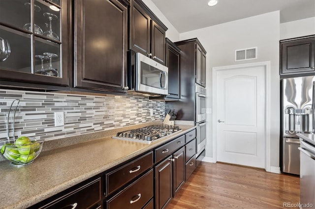 kitchen with light wood-type flooring, visible vents, tasteful backsplash, appliances with stainless steel finishes, and dark brown cabinets