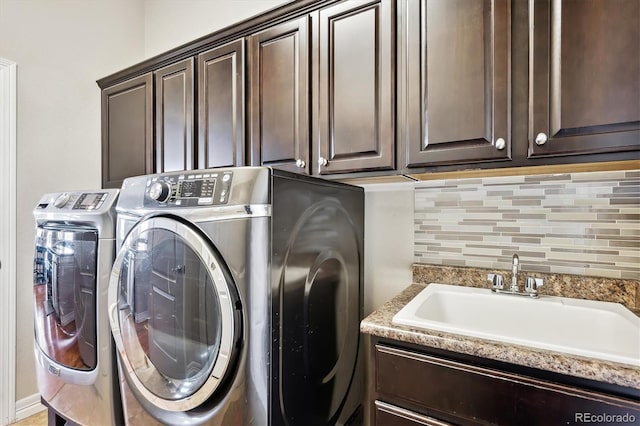 laundry room with cabinet space, independent washer and dryer, and a sink