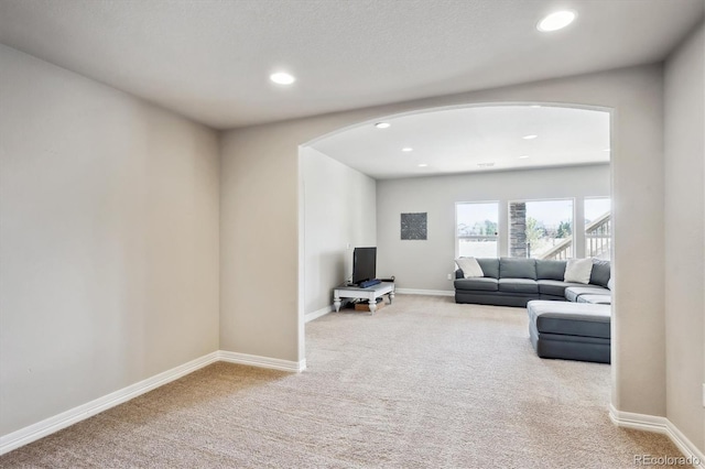 carpeted living area with arched walkways, recessed lighting, and baseboards