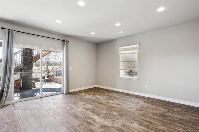 spare room featuring a wealth of natural light, baseboards, and wood finished floors