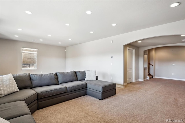 living area featuring stairway, baseboards, recessed lighting, arched walkways, and light colored carpet