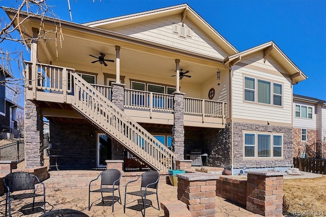 back of house featuring stairway, a ceiling fan, a patio, and stone siding