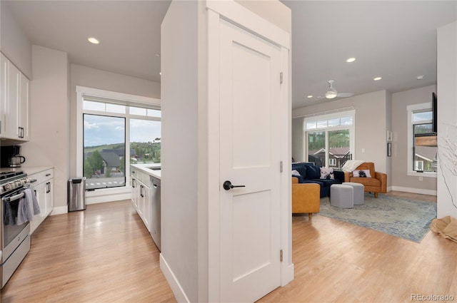 kitchen with appliances with stainless steel finishes, light hardwood / wood-style floors, white cabinetry, and ceiling fan