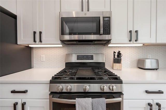 kitchen with white cabinets, appliances with stainless steel finishes, and backsplash