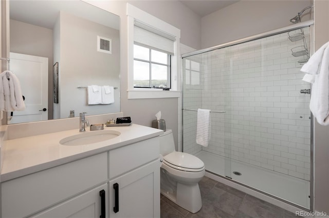 bathroom with tile patterned floors, vanity, a shower with shower door, and toilet