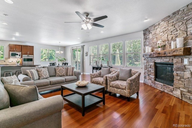25402 E Glasgow Pl, Aurora, CO 80016 - living area featuring dark wood-type flooring, ceiling fan, a stone fireplace, recessed lighting, and a chandelier