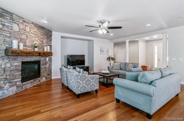 25402 E Glasgow Pl, Aurora, CO 80016 - living area with decorative columns, wood finished floors, ceiling fan, and a stone fireplace