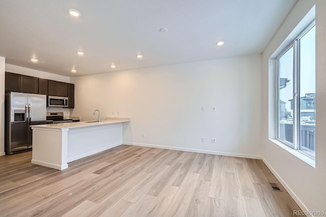 kitchen featuring kitchen peninsula, sink, light hardwood / wood-style floors, and appliances with stainless steel finishes