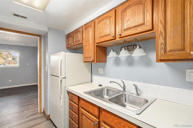 kitchen featuring white fridge, light hardwood / wood-style flooring, and sink