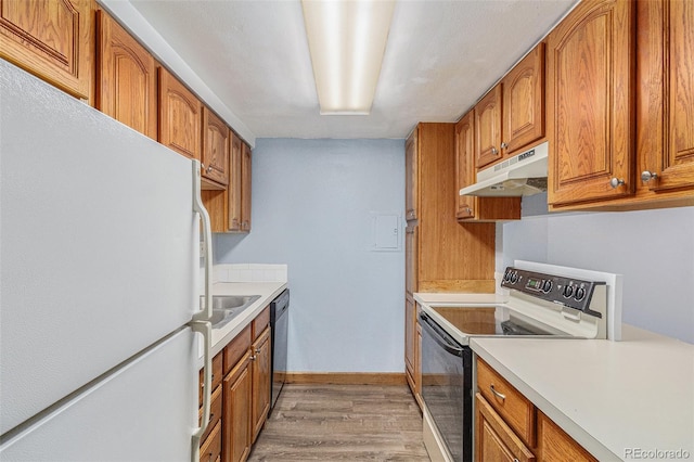 kitchen with light wood-type flooring, white appliances, and sink