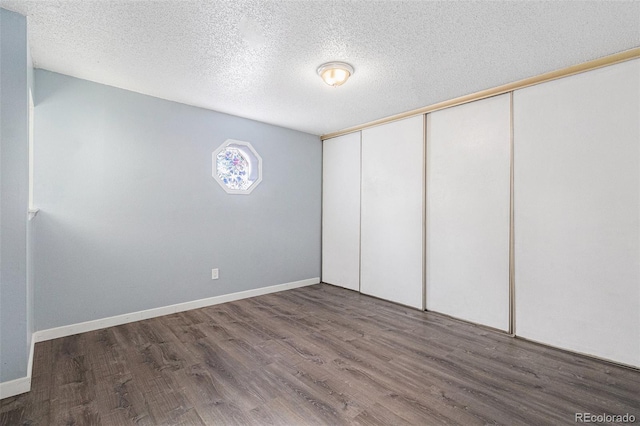 unfurnished bedroom featuring dark hardwood / wood-style flooring, a textured ceiling, and a closet