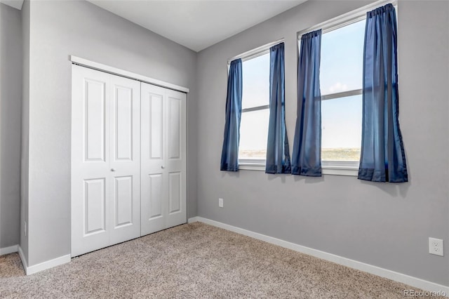 unfurnished bedroom featuring light carpet, a closet, and multiple windows