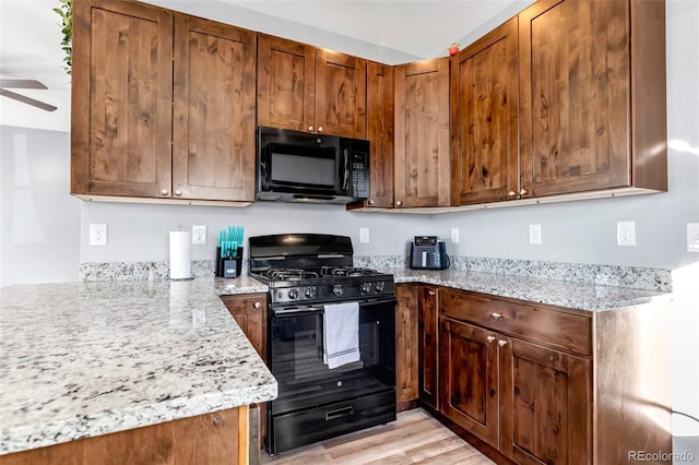 kitchen featuring light stone countertops, light hardwood / wood-style floors, ceiling fan, and black appliances