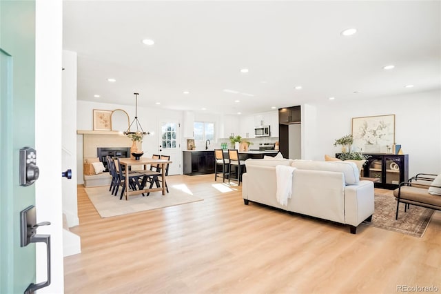 living area with recessed lighting, a glass covered fireplace, and light wood finished floors