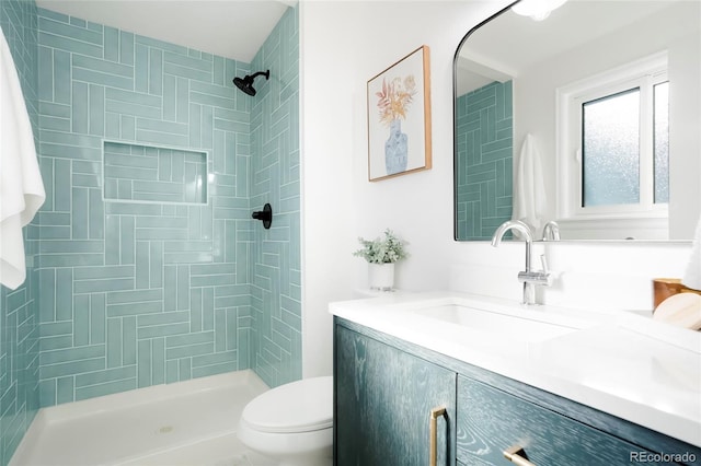 full bathroom featuring toilet, a tile shower, and vanity