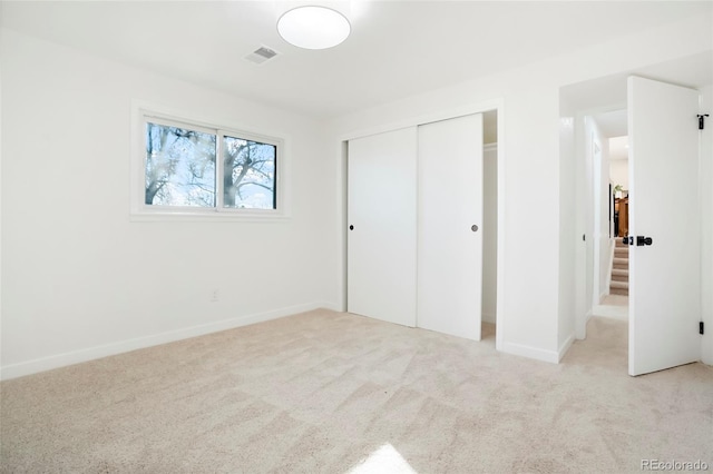 unfurnished bedroom featuring light carpet, baseboards, visible vents, and a closet