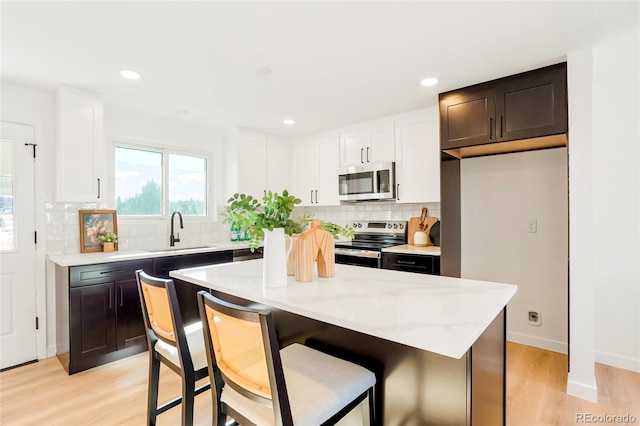 kitchen with backsplash, white cabinetry, stainless steel appliances, and a sink