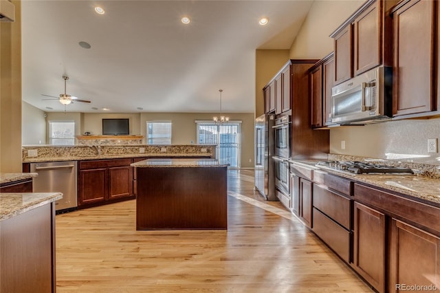 kitchen featuring light stone countertops, pendant lighting, a center island, and stainless steel appliances