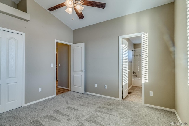 unfurnished bedroom with ceiling fan, high vaulted ceiling, connected bathroom, and light carpet