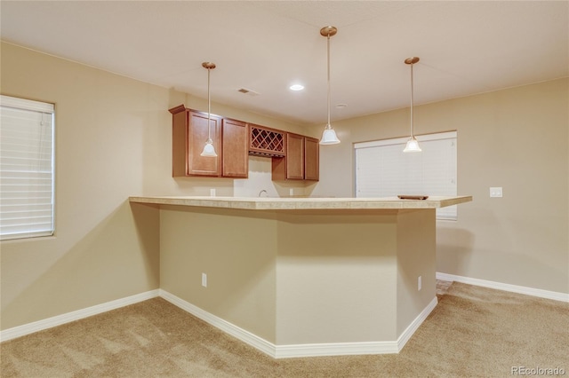 kitchen with decorative light fixtures, kitchen peninsula, a breakfast bar area, and light carpet