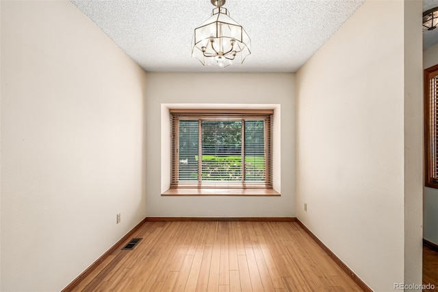 4207 S Granby Ct Unit A, Aurora, CO 80014 - empty room featuring a chandelier, wood finished floors, and a textured ceiling