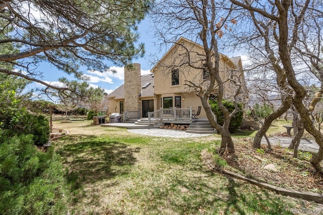 14536 Latrobe Dr, Colorado Springs, CO 80921 - back of property with stucco siding, a deck, a chimney, a lawn, and stone siding