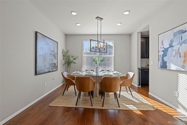 dining area featuring dark hardwood / wood-style floors and an inviting chandelier