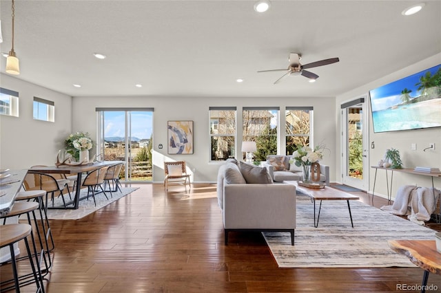 living room with dark hardwood / wood-style flooring, ceiling fan, and a healthy amount of sunlight