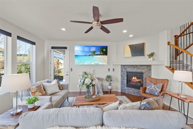 living room featuring ceiling fan, wood-type flooring, and a tile fireplace