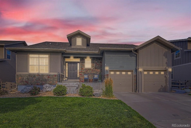 view of front facade featuring an attached garage, concrete driveway, a lawn, and stone siding