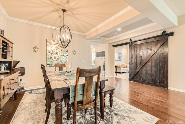 dining area featuring a barn door, baseboards, hardwood / wood-style floors, and ornamental molding